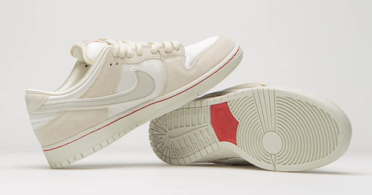 A pair of low-top Coconut Milk- and Light Bone-coloured Dunks with red details.