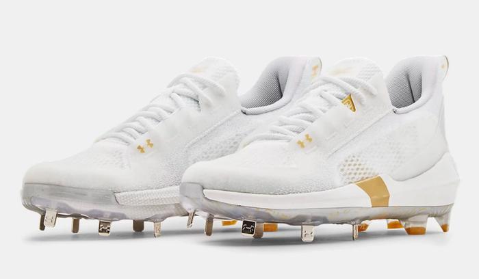 Best baseball cleats Under Armour product image of a pair of white and gold metal cleats.