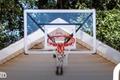Image of a red-rimmed basketball hoop with a clear backboard mounted to the top of a garage.