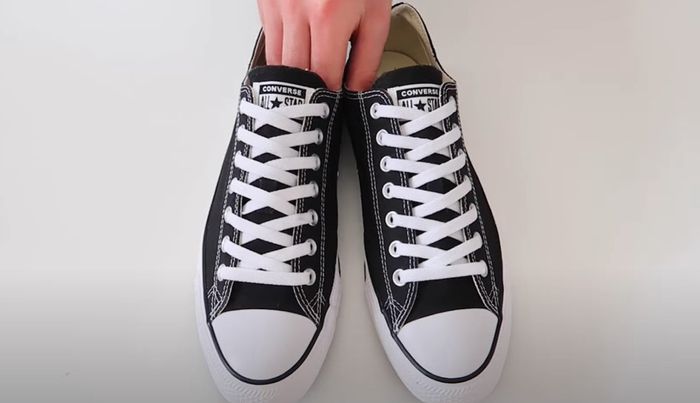 Converse product image of black sneakers with white laces done up to the top.