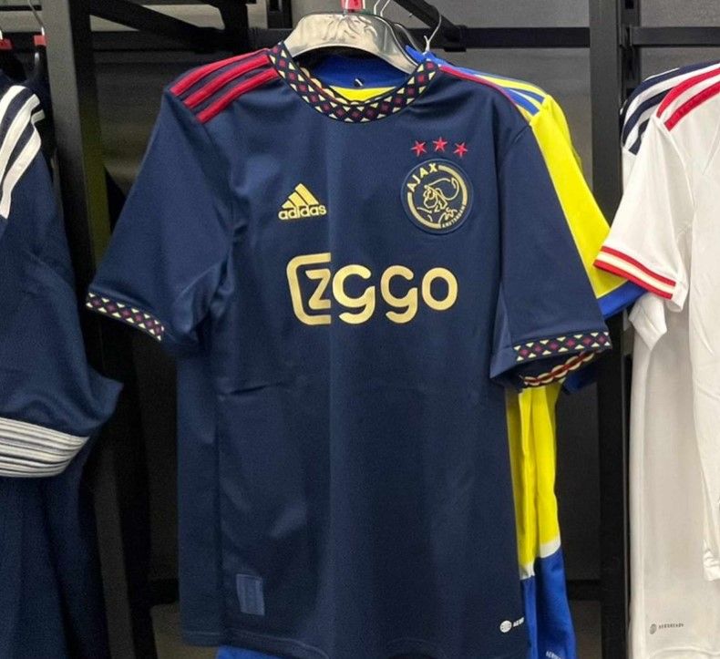 Ajax away kit 2022/23 product image of a navy shirt with red and gold details.