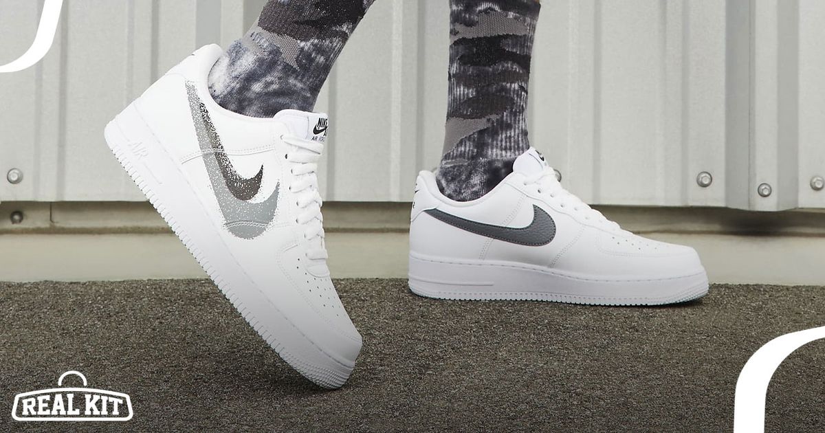 Someone in black and grey camouflage socks wearing white Air Force 1 Lows with double grey Swooshes down the sides.
