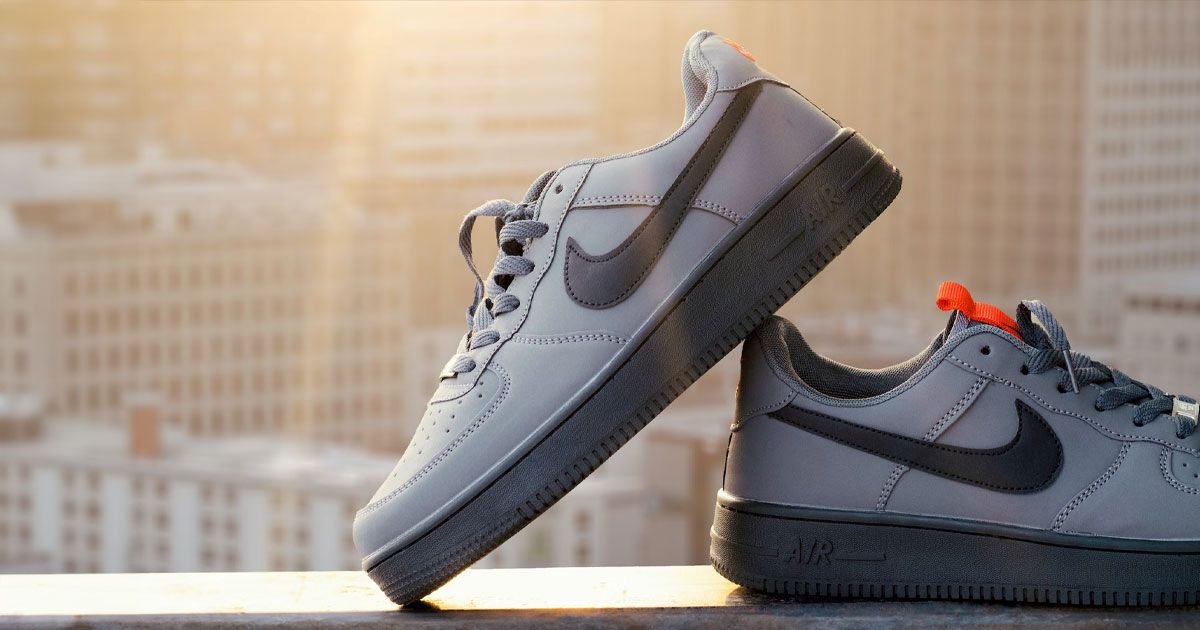 A grey Air Force 1 Low with a black Swoosh on the side and a black sole unit propped against another on a rooftop.