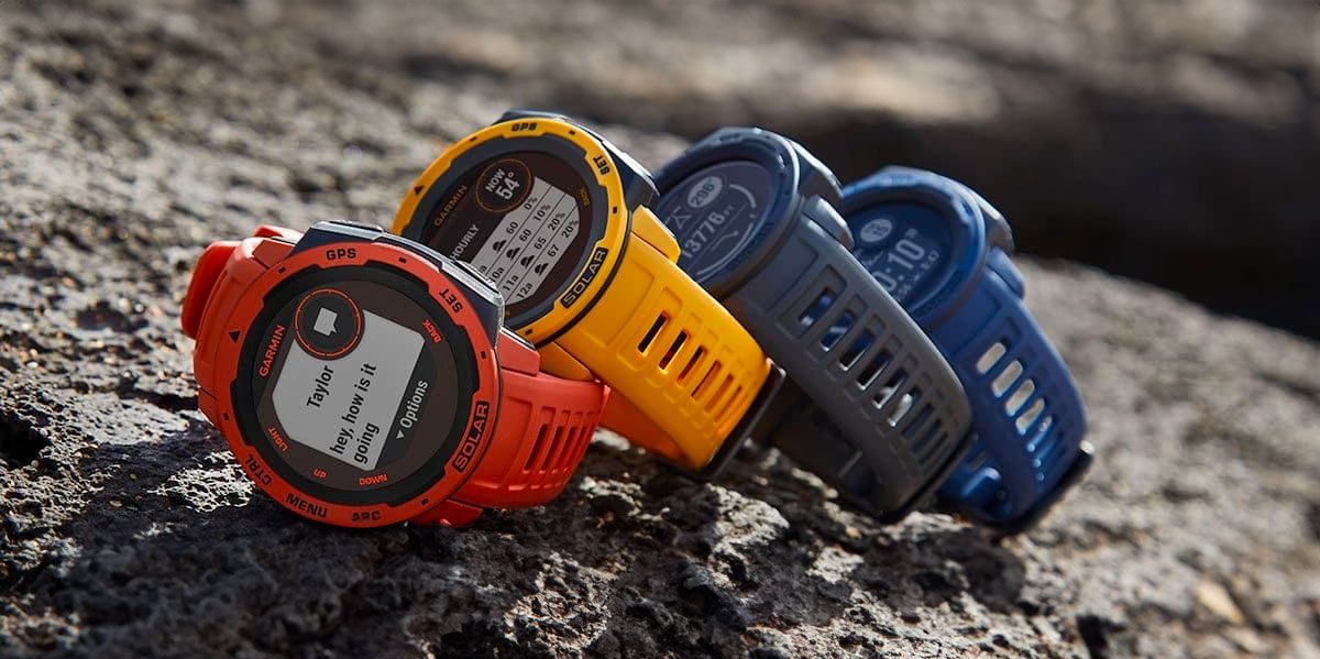 Image of four Garmin Instinct Solar smartwatches resting on a rock, one in red, one in yellow, one in black, and the last one in blue.