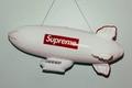 A white blimp model with the Supreme box logo in red on the side.