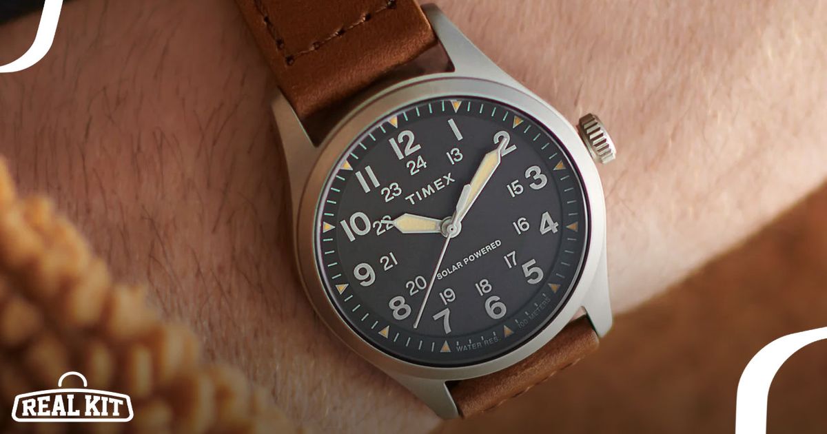 Close-up of someone wearing a silver analogue watch with a black watch face and brown strap.