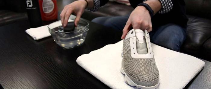FootJoy golf shoes being cleaned with a brush and water.
