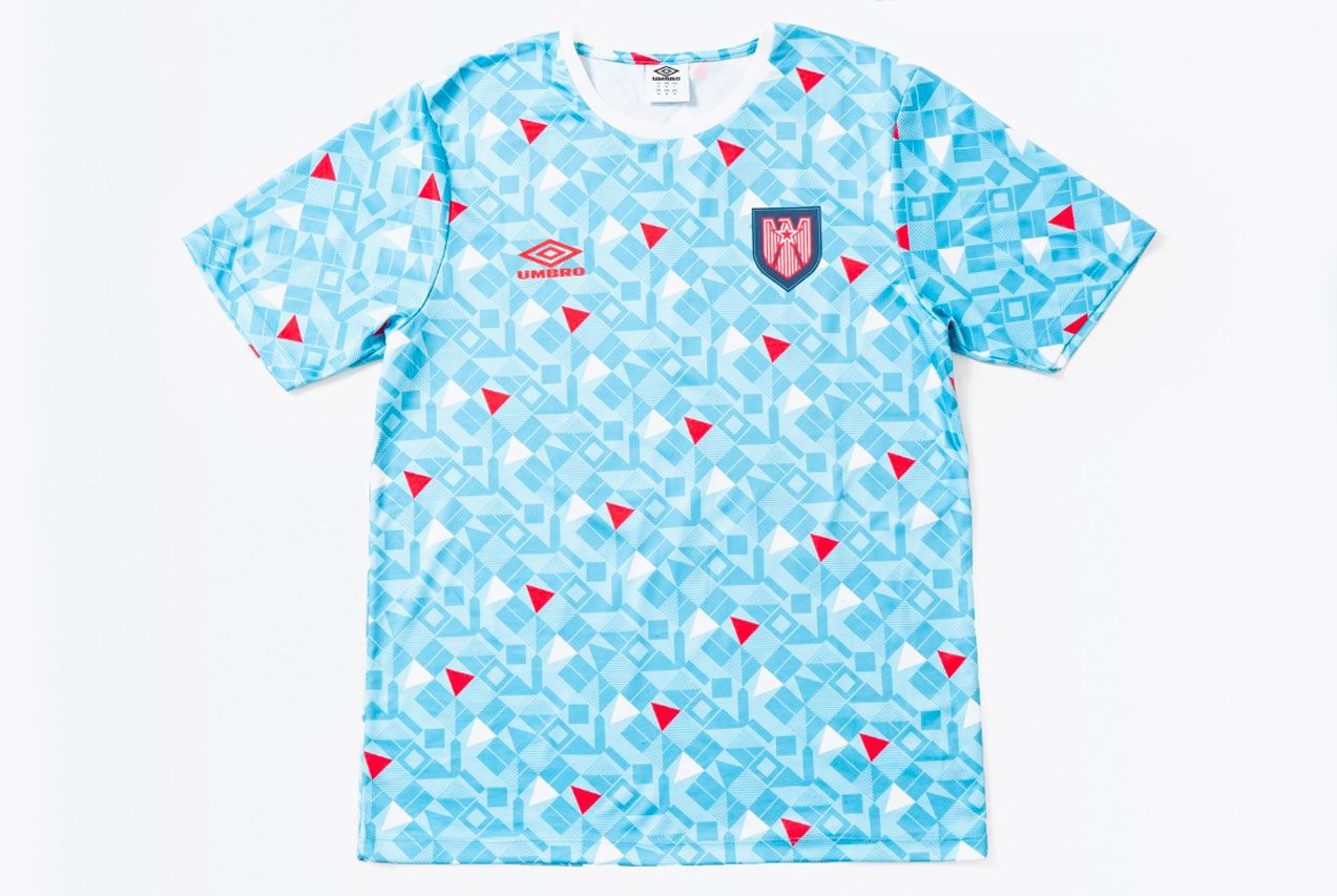 The Nations' Collection by Umbro product image of a light blue retro USA shirt with a white and red geometric pattern all over.