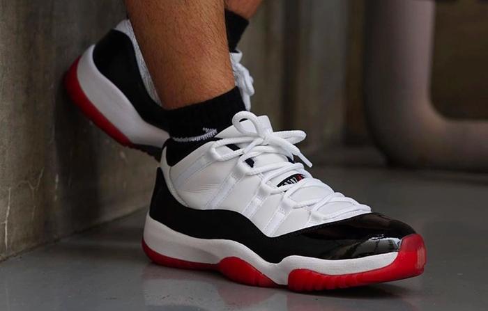 Air Jordan 11 Low "Concord Bred" product image of a pair of white sneakers with patent black leather overlays and a red sole.