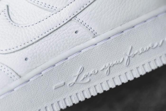 NOCTA x Nike Air Force 1 'Certified Lover Boy' product image of a triple-white sneaker with 'Love You Forever' embossed on the midsole.