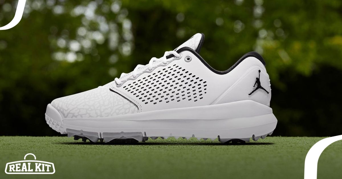 A white golf shoe with black lining and Jumpman logo toward the heel sat on a golf course.