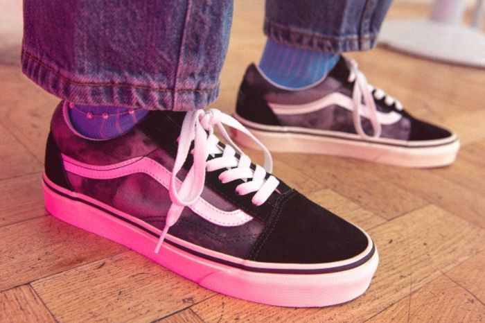 Vans product image of a pair of black shoes with crossed white laces on feet.
