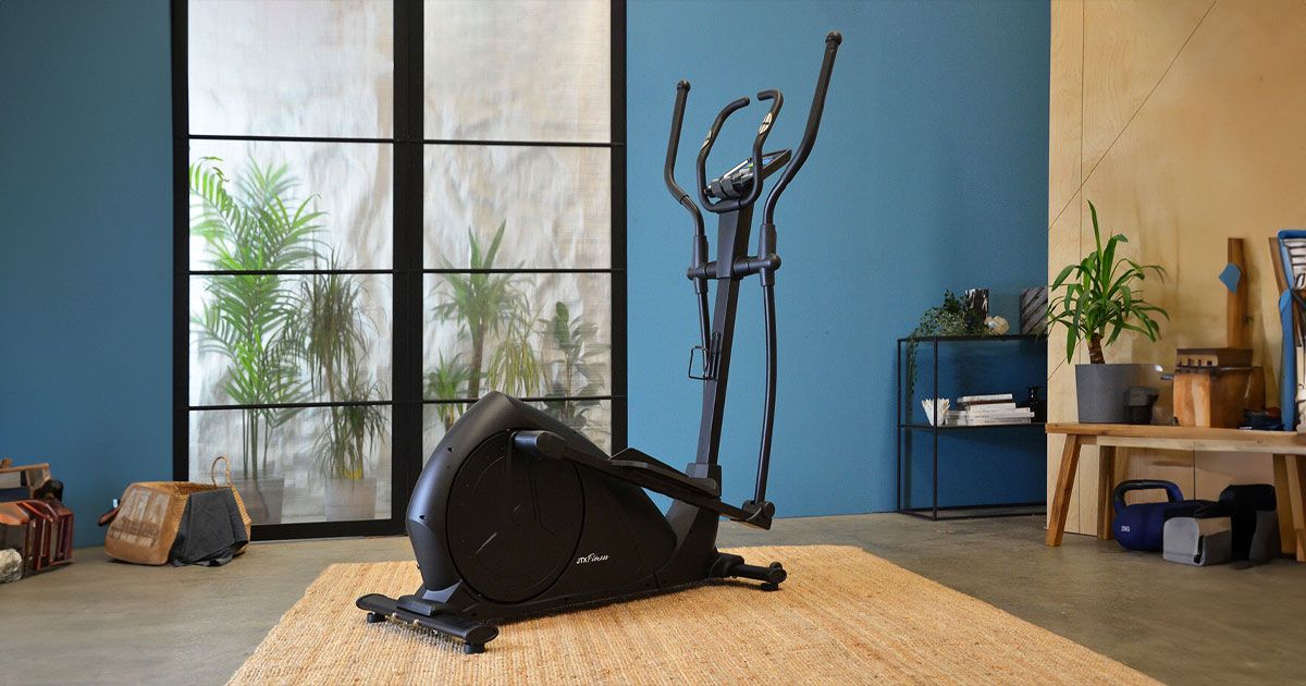 A black cross trainer in front of a window and blue wall.