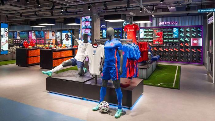 Picture of inside a SportsDirect store featuring mannequins wearing football kits and football boots on the walls.