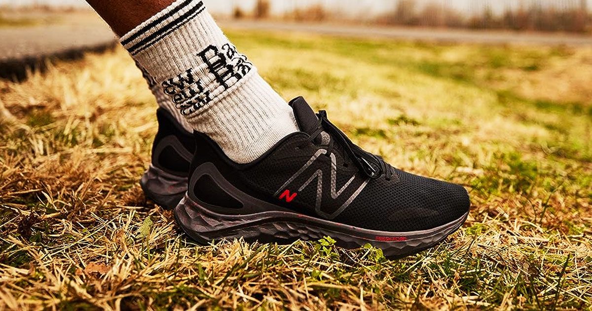 Someone in white socks with black writing and details on the sides wearing a pair of black New Balance running shoes.
