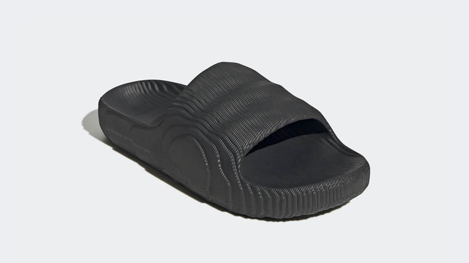 adidas Adilette 22 Slides product image of an all-black slider with a wavey, grooved pattern over the top.