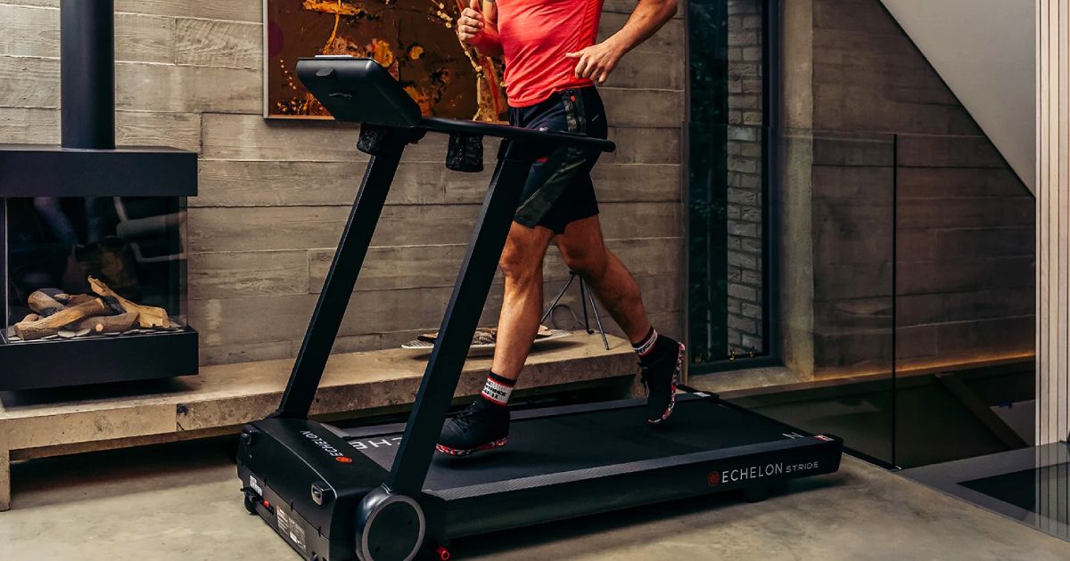 Someone in a red shirt and black shorts running on a black treadmill.