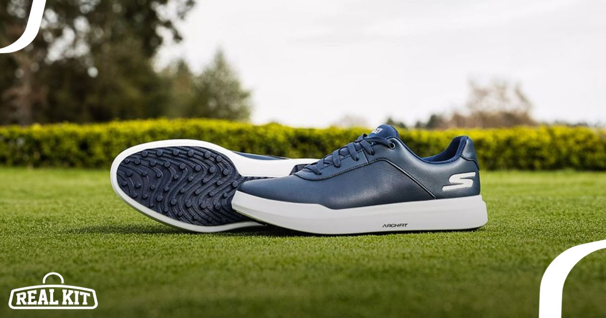 A pair of navy and white spikeless Skechers golf shoes laying on grass.