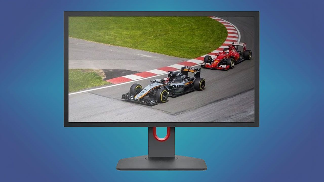 A dark grey monitor with red trim and two F1 cars racing on the screen in front of a dark blue and green gradient background.