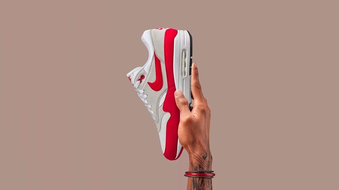 Air Max Day 2023 - Nike Air Max 1 "Anniversary" product image of a white and red sneaker held up by a hand.