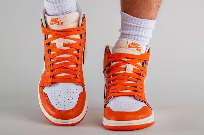 Air Jordan 1 High OG "Starfish" product image of a white leather sneaker with orange overlays and black details.