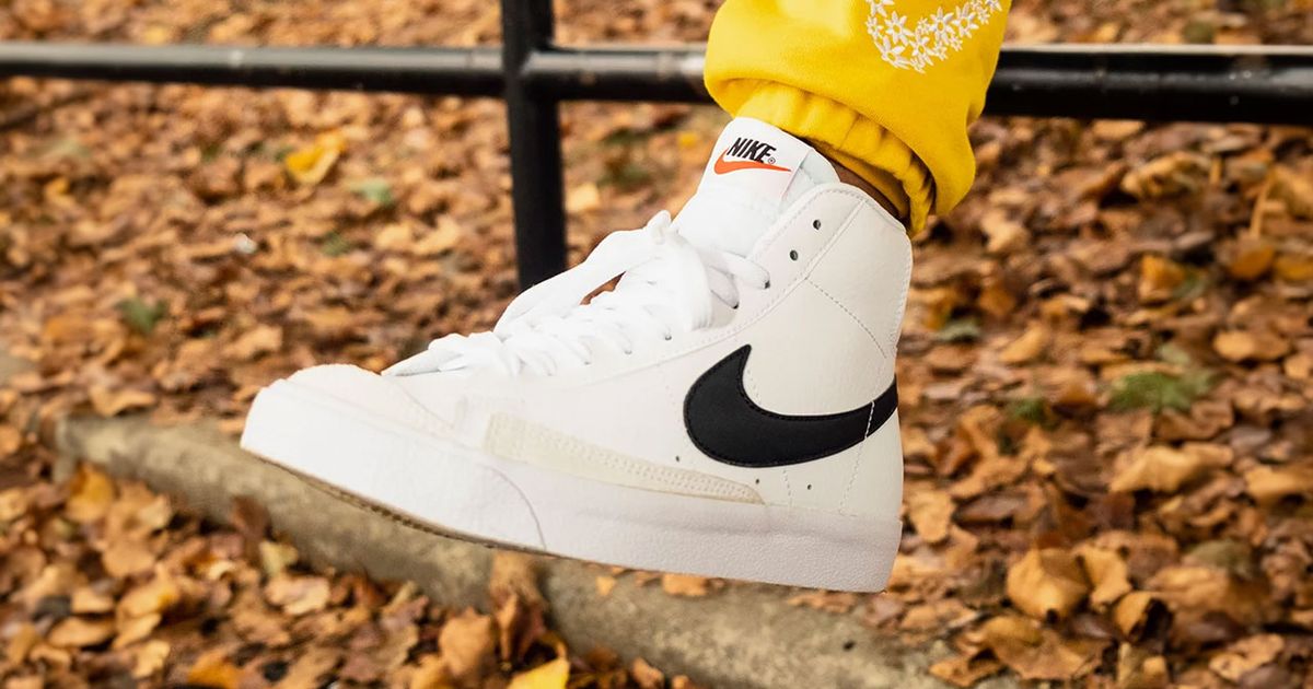 Someone in yellow joggers wearing a white Nike Blazer Mid featuring a black Swoosh down the side.
