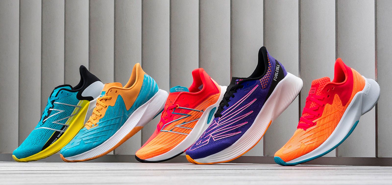 A selection of multi-coloured New Balance running shoes, including orange, blue, and purple options.