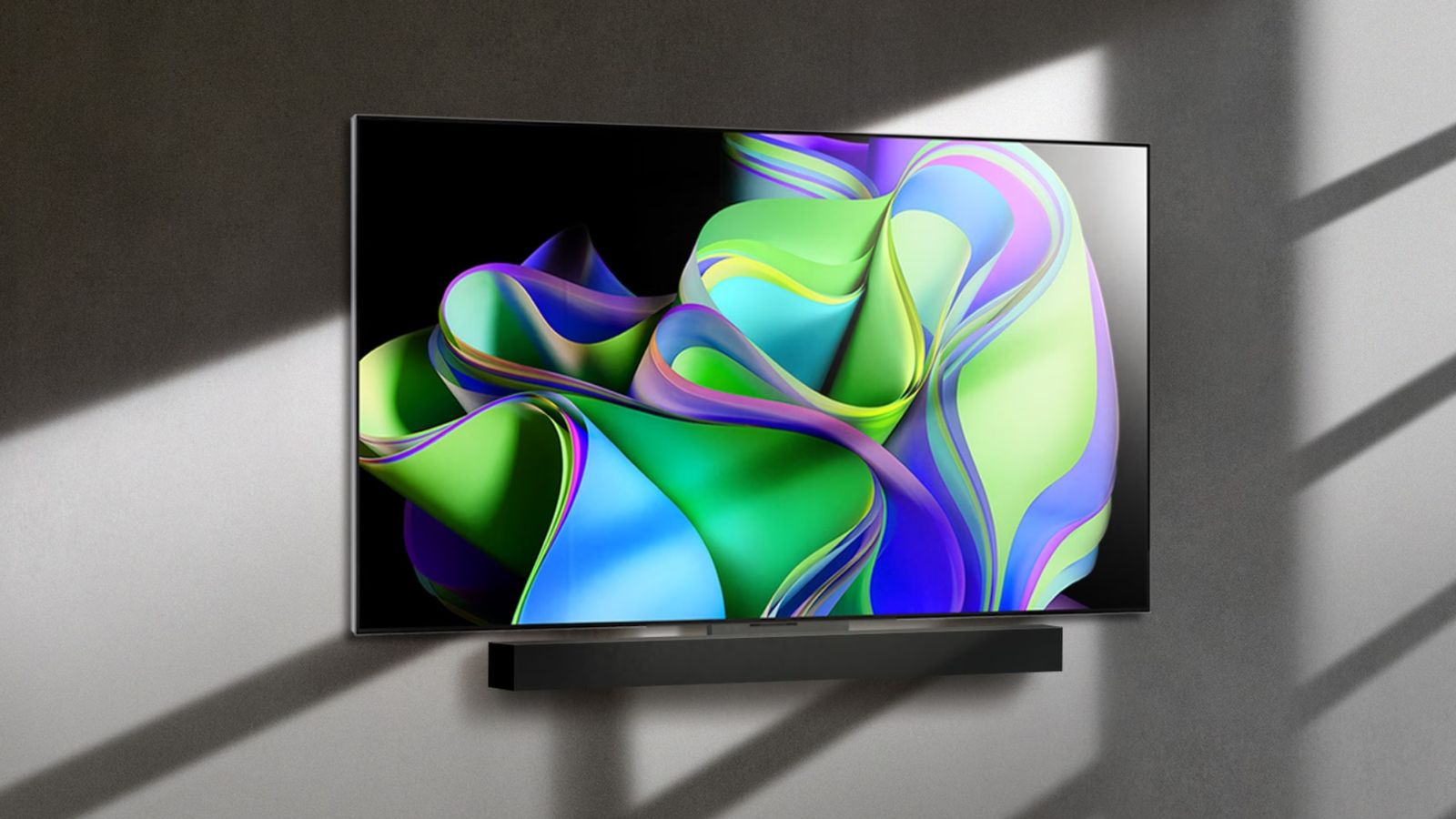 LG OLED evo C3 product image of a flatscreen TV mounted to a grey wall featuring a green, purple, and blue wavy pattern on the display.