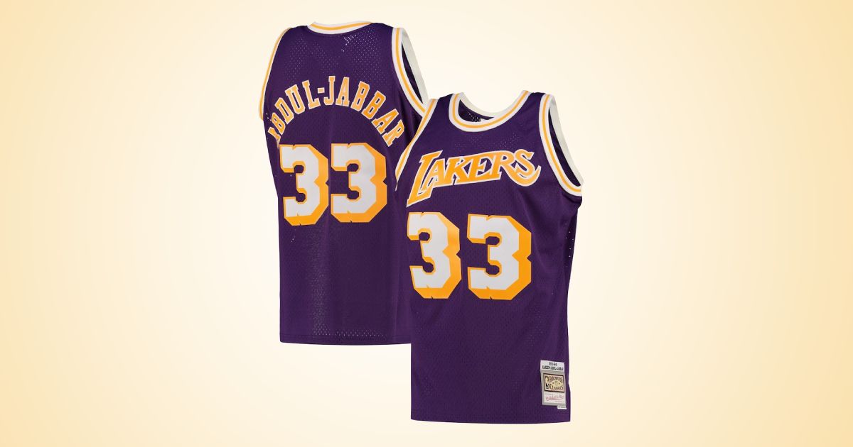 A purple Lakers jersey with gold and white trim and lettering in front of a gradient white and orange background.