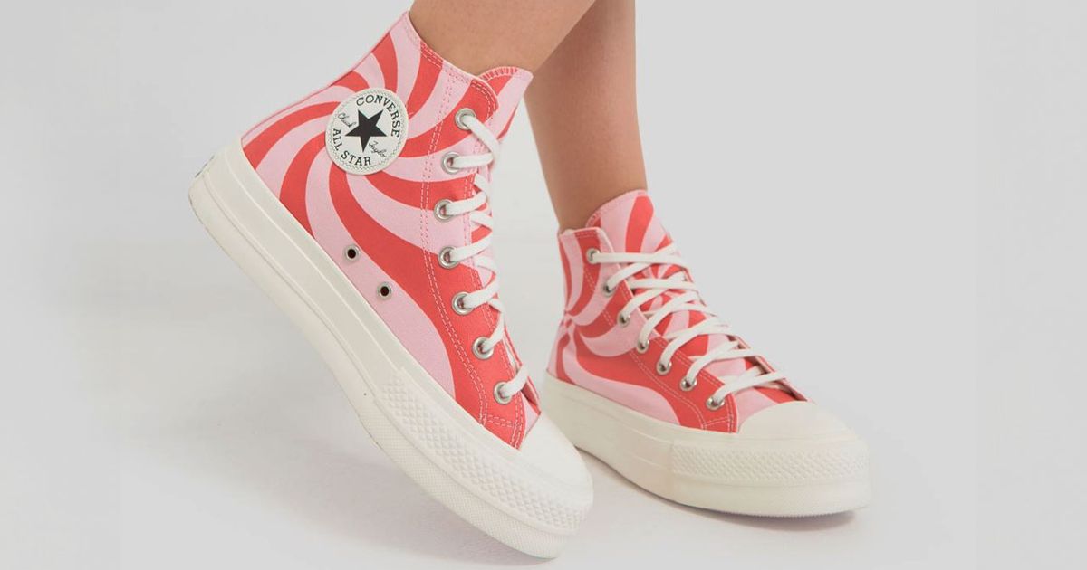Someone wearing a white pair of swirly Converse high-tops in two different pink tones, featuring off-white soles and toeboxes.