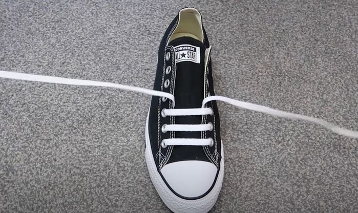 Converse product image of a black sneaker with white laces straight over the tongue.