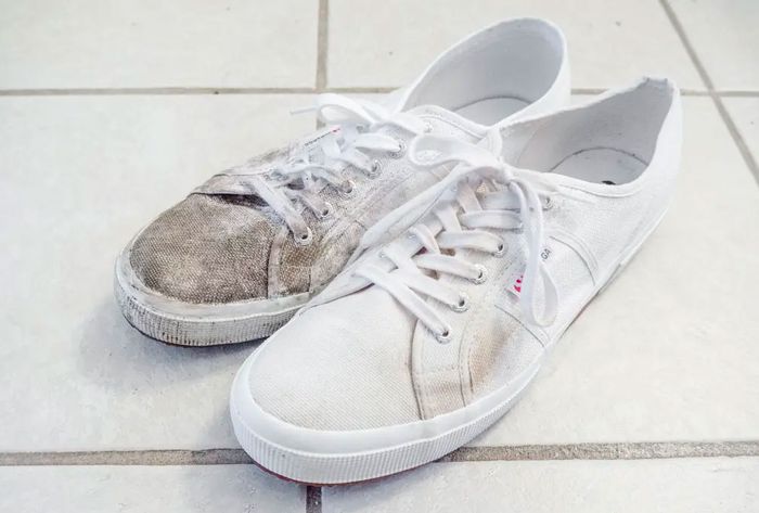 A pair of white canvas shoes, one covered in mud, the other clean.