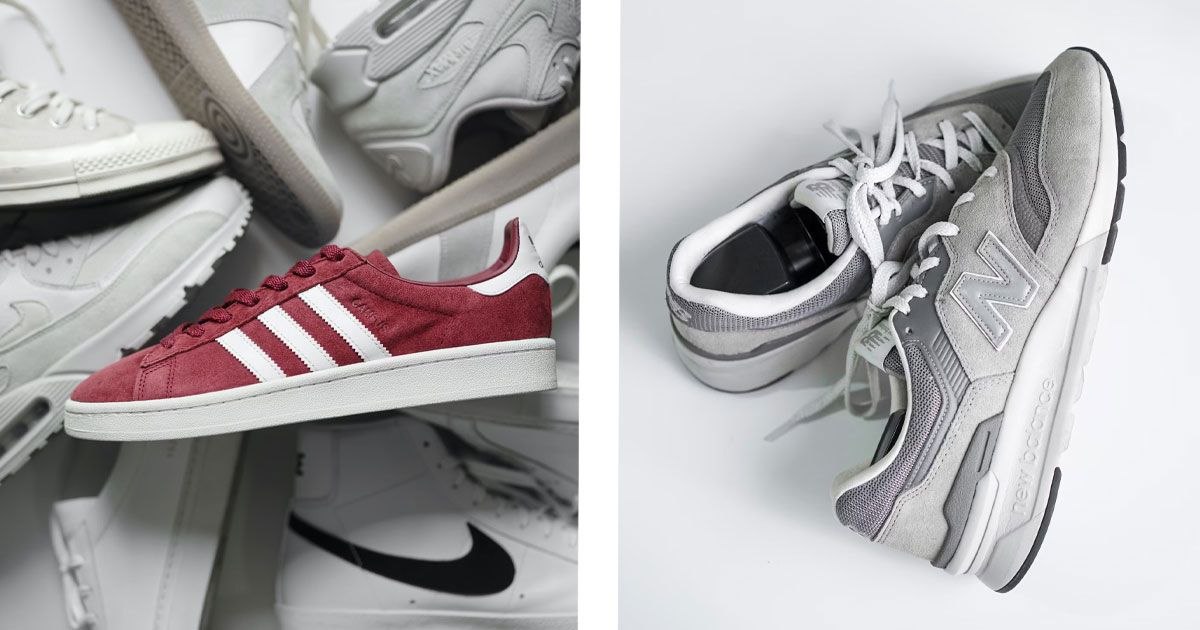 A red adidas shoe with white details and midsole laying on a pile of white shoes on the left. On the right, a pair of silver, grey, and white New Balance shoes.