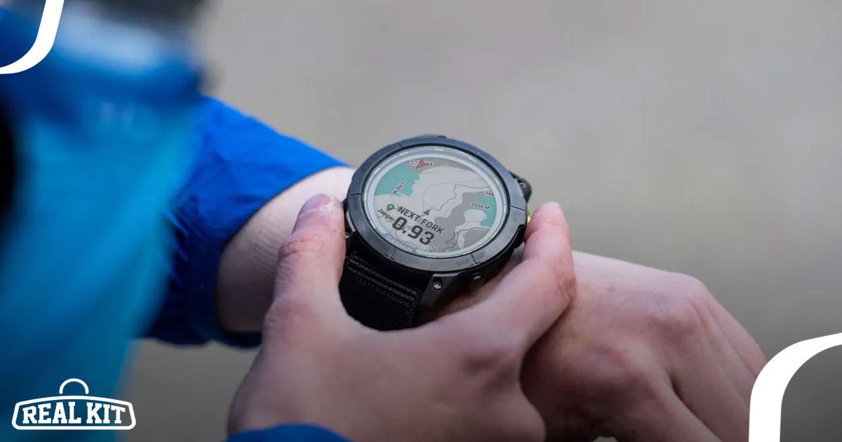 Someone in a blue jacket adjusting his black Garmin watch with a map on the display.