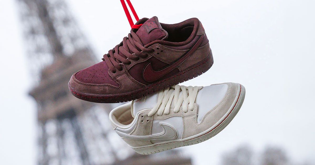 A burgundy Nike SB Dunk Low hanging from a red lace above a coconut milk-coloured low-top.