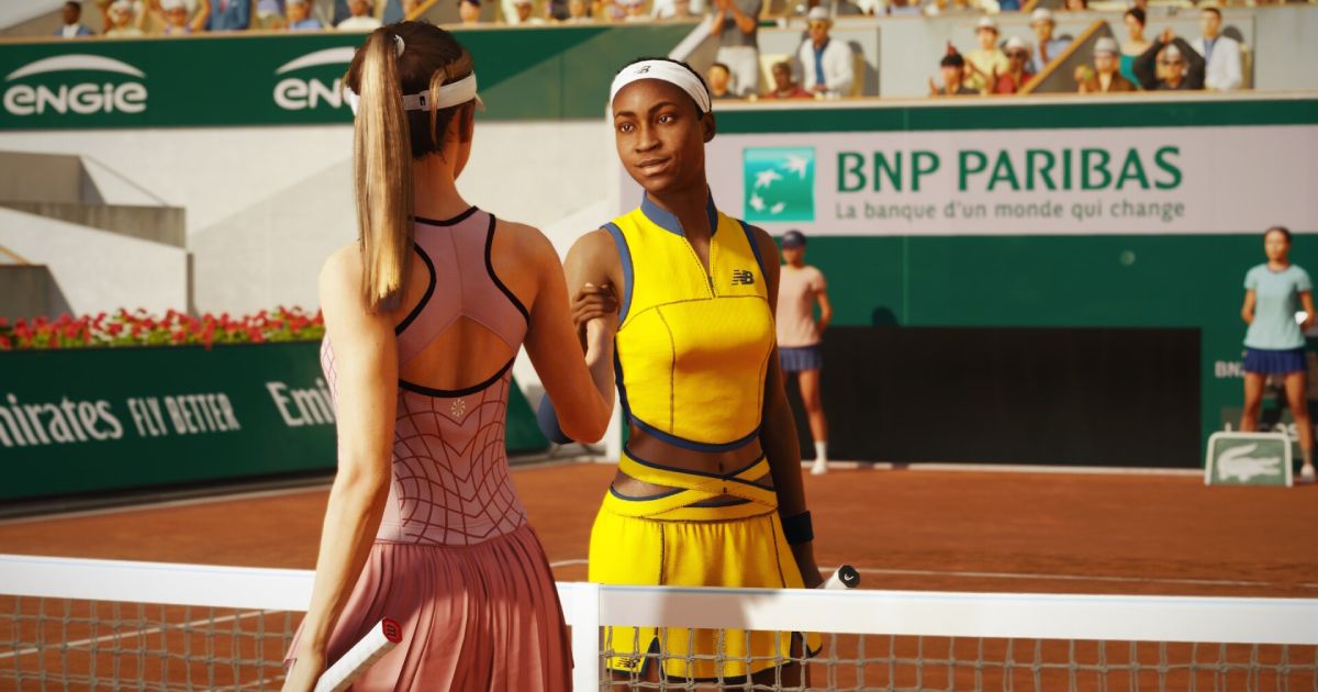Two women, one in yellow and the other in pink, shaking hands over the net on a clay court in TopSpin 2K25
