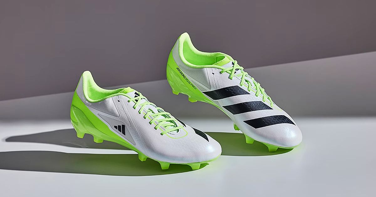 A pair of white rugby boots with lime green trim and three black stripes down the inner sides.