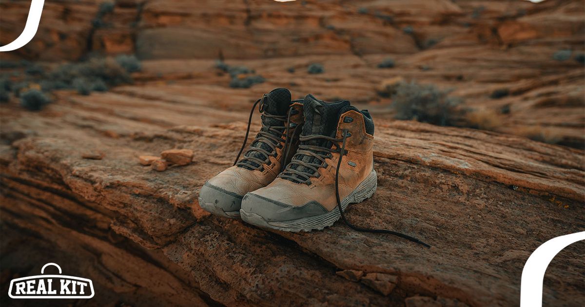 A pair of light brown hiking boots with black laces and tongues sat on the edge of an orange-rock cliff.
