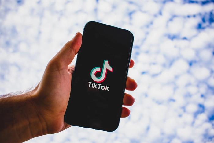 How to see videos you reposted on TikTok man holding phone